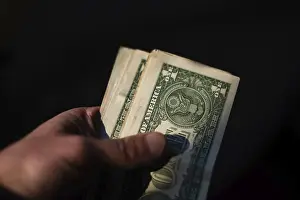 US Currency Stampe: A hand holds a stack of US currency