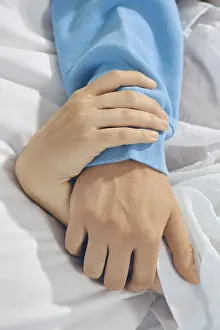 Couple In Bed Stampe: Two hands are held together on bed sheets