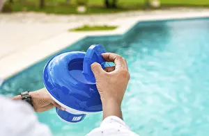 Swimming Pool Disinfection Stampe: Hands of a worker installing a pool chlorine float