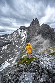 Dramatic Clouds Europe Stampe: Hiker looking at mountains under dramatic clouds