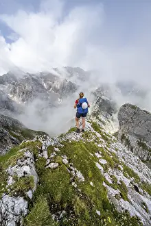 Hiking In Southern Germany Stampe: Hiker looking at mountains under dramatic clouds