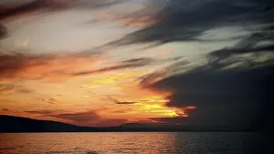 Cloudy Evening Sky In Europe Stampe: Intense sunset with dramatic cloud formations over water