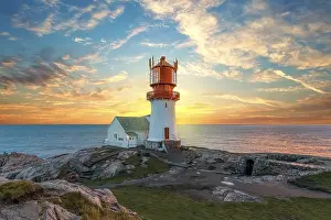 Lighthouse At Sunset Stampe: Lighthouse surrounded by rocks at sunset