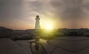 Lighthouse At Sunset Stampe: Lighthouse surrounded by rocks at sunset