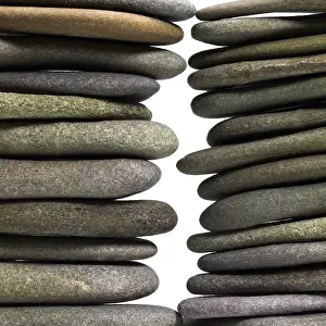 Deserted Beach Landscape Stampe: Low angle view of two flat pebble stone stacks in light back