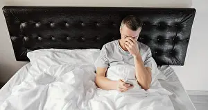 Dark Bedroom Scene Stampe: Man bed using mobile