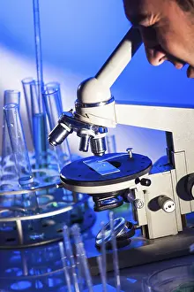 Laboratory Equipment Usage Stampe: Man is looking into the ocular of microscope