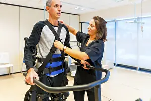 Physical Disability Support Stampe: Mechanical exoskeleton. Female physiotherapy medical assistant with disabled person lifted with robotic skeleton