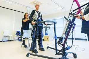 Physical Therapy Exercises Stampe: Mechanical exoskeleton. Female physiotherapy medical assistant lifting disabled person with robotic skeleton