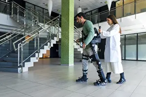 Mechanical Exoskeleton Stampe: Mechanical exoskeleton, female doctor physiotherapist walking with disabled person helped by robotic skeleton