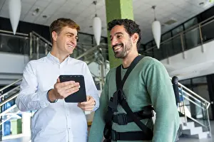Physical Therapy Treatment Stampe: Mechanical exoskeleton, physiotherapist looking at consultation with tablet with disabled person with robotic skeleton