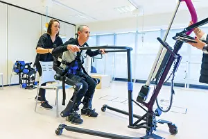 Mechanical Exoskeleton Stampe: Mechanical exoskeleton. Female physiotherapy medical assistant lifting disabled person with robotic skeleton