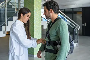 Mechanical Exoskeleton Stampe: Mechanical exoskeleton, female physiotherapist doctor putting tapes on disabled person with robotic skeleton