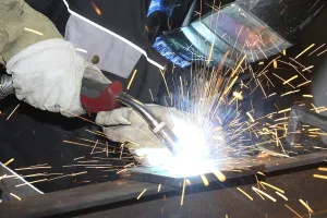 Workplace Safety Stampe: Metalworker during welding work in his workshop