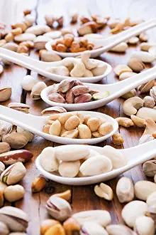 Deserted Table Scene Stampe: Mix of nuts over a rustic table in backlit