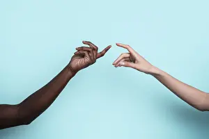 Diversity And Inclusion Stampe: Two multiethnic hands reach toward each other against a solid blue backdrop