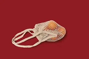 Single Colored Background Photo Stampe: Oranges in a string bag on ruby red background