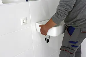 Plumber Installation Stampe: Plumber installs a new washbasin
