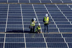 Solar Panel Inspection Stampe: Three engineers inspect a large solar panel array together