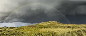Deserted Dune Landscape Stampe: Rainbow with dramatic rain clouds over dune landscape