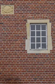 Red Brick Facade Stampe: A rectangular window and a coat of arms in a red brick facade