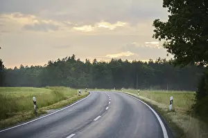 Southern Germany Weather Forecast Stampe: Road through fields and forests at sunset after rain