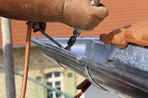 Residential Building Construction Site Stampe: Roofer doing tinsmith work on a gutter