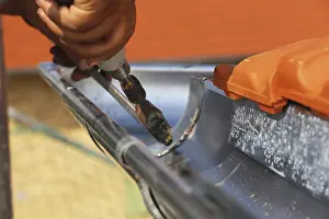 Residential Building Repair Stampe: Roofer doing tinsmith work on a gutter