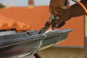 Residential Building Construction Site Stampe: Roofer doing tinsmith work on a gutter