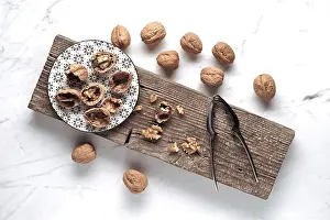 Wooden Board Arrangement Stampe: A rustic setup features whole and cracked walnuts on a patterned plate
