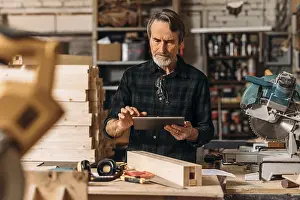 Male Craftsman Stampe: Senior carpenter using a digital tablet in his workshop