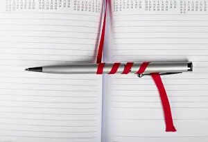 Office Supply Desk Utensils Stampe: Silver pen on opened notebook with red string