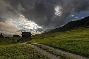 Mittenwald Travel Photography Stampe: Small hut on mountain meadow with path and dramatic cloud sky