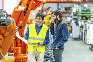 Metal Fabrication Technology Stampe: Software engineer explaining to controlling robotic welding process to welder in factory
