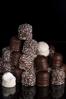 Assorted Chocolates Stampe: A stack of different chocolate kisses on a dark background with a reflection