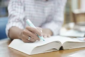 Laptop Computer Use Stampe: A student writes notes in a notebook while studying in a library