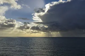 Sunbeams Over Water Stampe: Sunrays shining through clouds over the sea