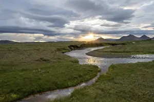 Sunset In Iceland Stampe: Sunset between clouds, river flowing through meadows