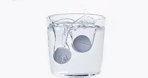 Full Body Length Tablet Drop Stampe: Tablets Falling and Dissolving into a Glass of Water against White Background