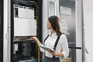 Data Center Professional Stampe: Technician using tablet pc while analysing server in large data center