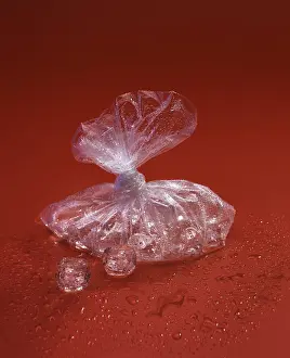 Live Still Life Photography Stampe: Translucent plastic bag with ice cubes on a red surface