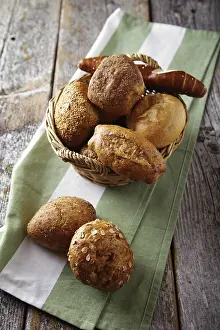 Freshly Baked Goods Stampe: Various types of bread in a basket lying on a rustic table