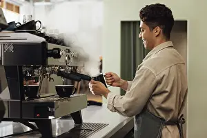 Coffee Machine Stampe: Side view of a barista using a coffee machine