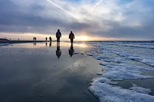 Evening Sun Germany Stampe: Walkers at sunset on the beach