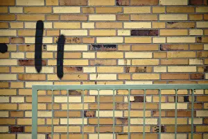 Old Building Architecture Stampe: A wall made of old clinker bricks with an angular railing in front of it