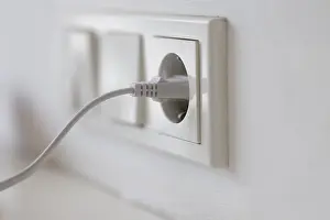 Power Supply Concept Stampe: White power plug in a socket on the wall