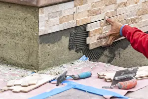 Building Construction Site Stampe: Worker installing wall tile at construction site