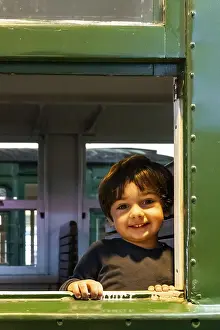 Boy Looking At Camera Stampe: A young boy is smiling at the camera from a train window