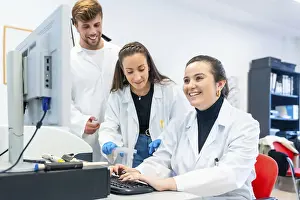 Healthcare Professionals Working Together Stampe: Three young doctors working in a scholarship in a laboratory using computer to analyse data