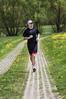 Sportsman In Action Stampe: A young man jogging through the fields